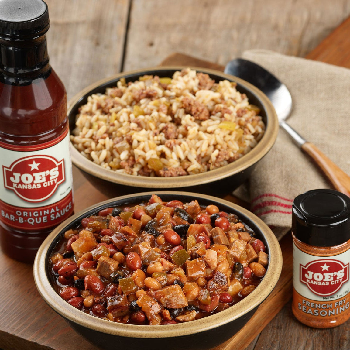 Bowl of BBQ beans, savory dirty rice, seasoned French-style potatoes, and extra sauces, showcasing Joe’s Kansas City BBQ sides and extras that can be added to any shipped meal kit or customized package.